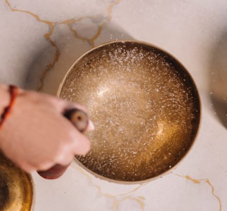 Close-up of a woman’s hand playing on a Tibetan bowl filled with water Close-up of a woman's hand playing on a Tibetan bowl filled with water.